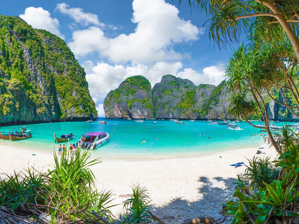 Spiaggia tropicale con barche tradizionali e mare turchese in Thailandia
